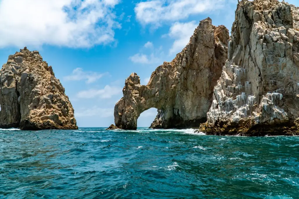 U.S. Issues Security Alert Near Los Cabos Airport: What Travelers Should Know 1 A natural rock arch, El Arco, stands in the turquoise ocean with two large rock formations on either side, under a blue sky with white clouds.