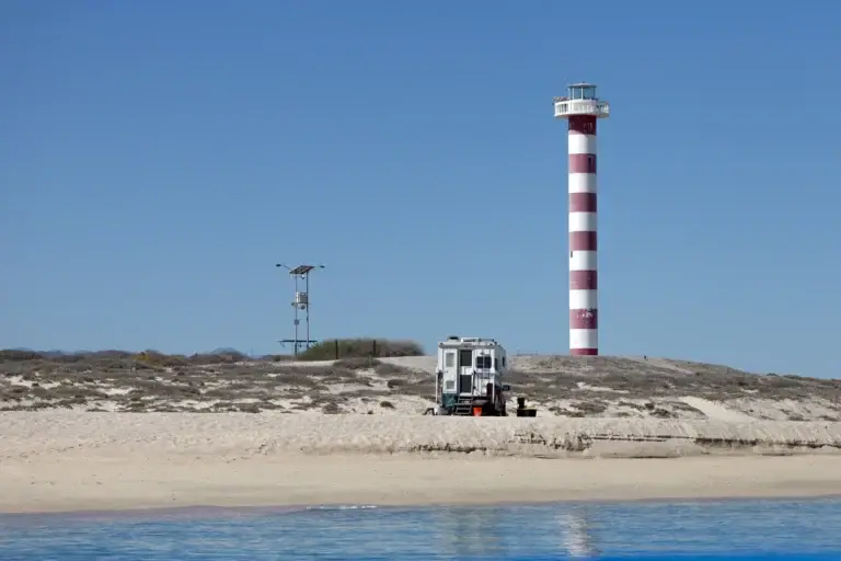 La Ventana & the Cerralvo Channel 1 Camper rig parked on the sand beside a lighthouse on a Baja beach